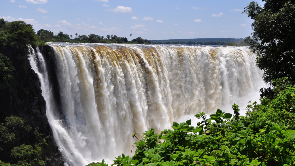 Victoria Falls peak flow wide shot Zimbabwe Zambezi River full curtain lush green