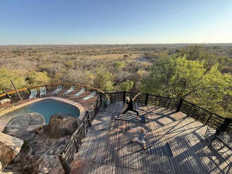 A guest practising yoga on the pool deck at Khami Lodge above the bush
